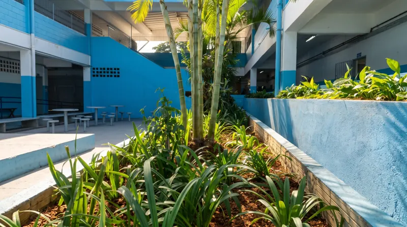 Canteiro de paisagismo com palmeiras areca, agapanto e espatifilos em pátio institucional, com cobertura de casca de pinus